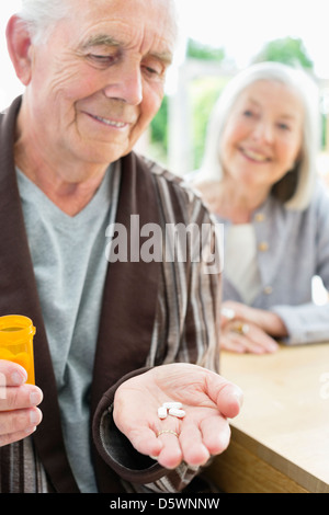 Uomo anziano con manciata di pillole Foto Stock