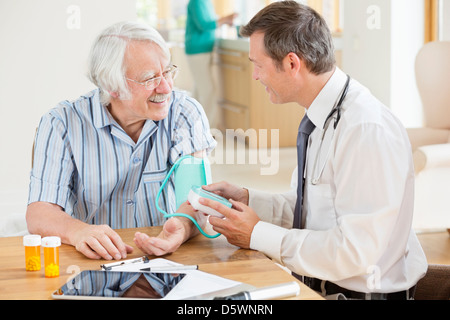 Medico più vecchi test di pressione del sangue del paziente a casa chiamata Foto Stock