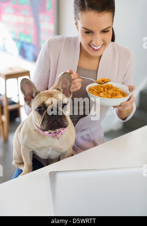 Donna mangiare cereali con il cane al giro Foto Stock