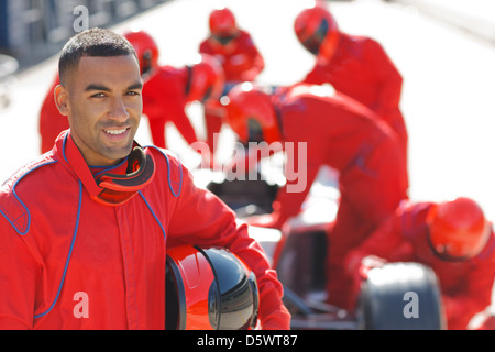 Racer in piedi con la squadra in pit stop Foto Stock