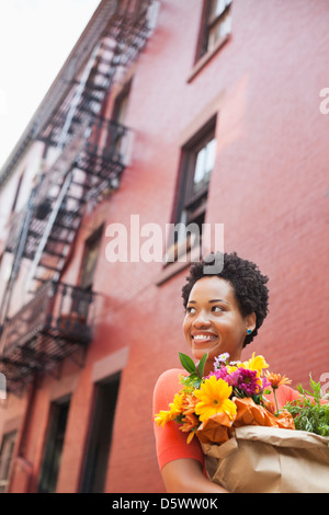 Donna borsa per il trasporto di fiori sulla strada di città Foto Stock