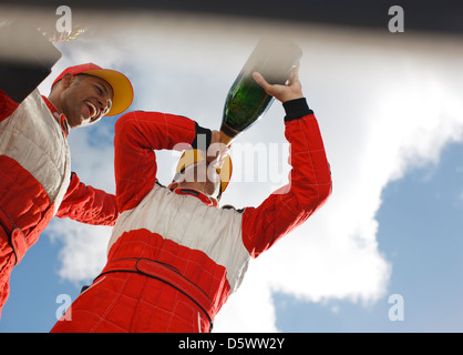 Racer bevendo champagne sulla via Foto Stock