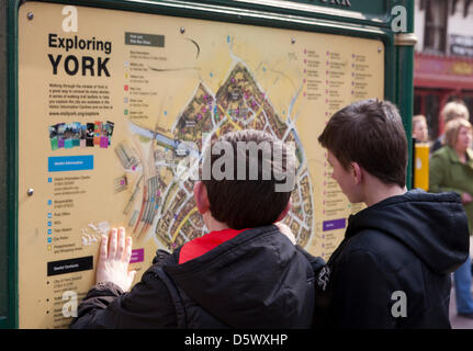 York City, North Yorkshire, Regno Unito, martedì 9 aprile 2013. Owen e Sam Elias riferendosi alla cartina stradale di York per guardare la strada animatori, licenza buskers, i turisti e la folla in York centro retail godendo il sole primaverile e le attrazioni nel quartiere centrale degli affari. Foto Stock