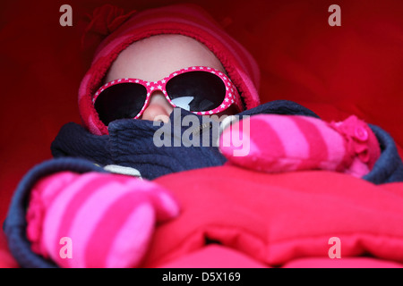 Un bambino indossa sfumature, guanti e un cappello. Foto Stock