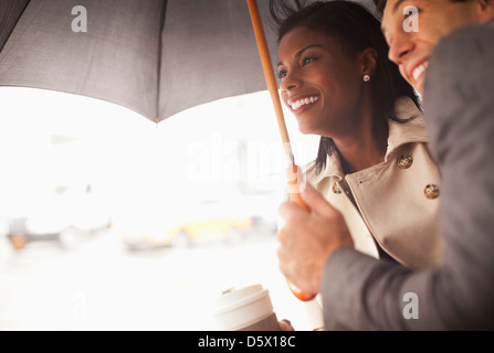 Gli imprenditori accoccolati sotto ombrellone Foto Stock