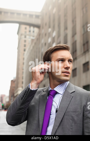 Imprenditore ascolto di auricolari su strada di città Foto Stock