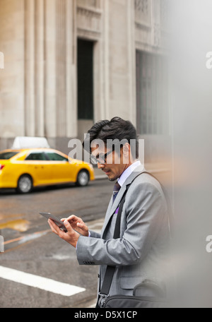 Imprenditore utilizzando computer tavoletta su una strada di città Foto Stock