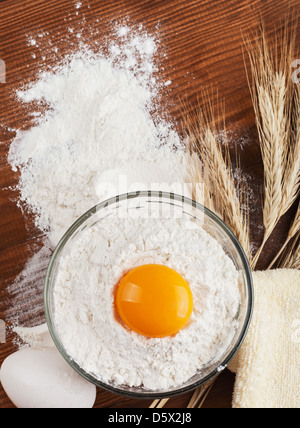 Preparare gli ingredienti per la cottura. Farina, uova su un tavolo di legno. spikelets di grano Foto Stock