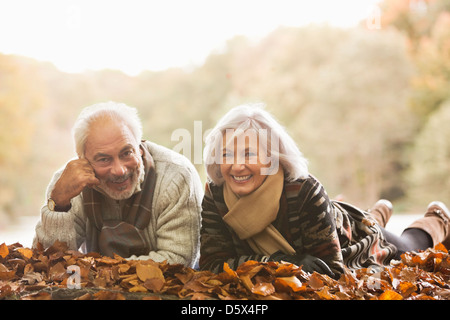 Coppia di anziani che stabilisce in foglie di autunno Foto Stock