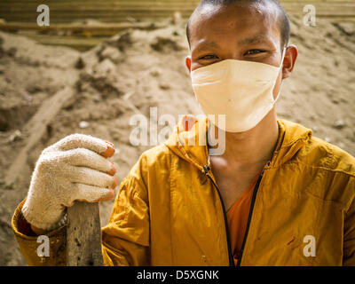 7 aprile 2013 - Chiang Mai e Chiang Mai, Thailandia - un debuttante buddista che indossa una maschera per bloccare il fumo e le sostanze inquinanti si prende una pausa durante il lavoro con i suoi compagni di novizi a Wat Jetlin a Chiang Mai. ''La masterizzazione di stagione," che va grossomodo dalla fine di febbraio alla fine di aprile è quando gli agricoltori nel nord della Thailandia masterizzare l'erba Morta e lo scorso anno la stoppia fuori i loro campi. La masterizzazione crea nuvole di fumo che provoca problemi di respirazione, riducono la visibilità e contribuisce al riscaldamento globale. Il governo thailandese ha vietato la masterizzazione e sta compiendo uno sforzo di controllo, ma gli agricoltori th Foto Stock