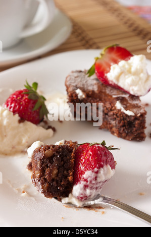 Delizioso boccone di Brownie al cioccolato e fragole con panna montata Foto Stock