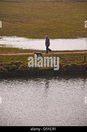 Maschio cani a piedi lungo la riva del fiume Foto Stock