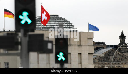 La bandiera svizzera (C) è volato oltre l'ambasciata di Svizzera accanto a un Tedesco e una bandiera europea a Berlino, Germania, 05 aprile 2012. Sullo sfondo il Reichstag può essere visto. La Germania e la Svizzera hanno convenuto dopo lunghi negoziati che gli averi tedeschi che sono stati trasferiti in Svizzera negli ultimi dieci anni sono essere tassato con fino al 41 per cento. Foto: WOLFGANG KUMM Foto Stock