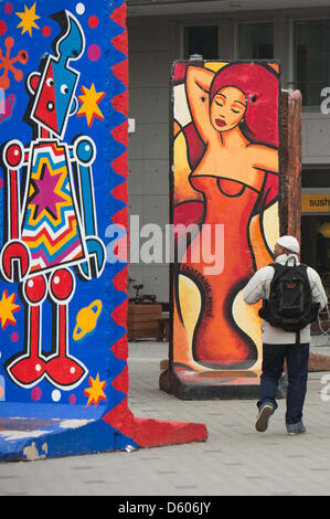 Un passante da passeggiate attraverso la 'Pop Art pareti', pezzi originali del muro di Berlino, a ex valico di frontiera Checkpoint Charlie a Berlino, Germania, 10 aprile 2013. Foto: MAURIZIO GAMBARINI Foto Stock