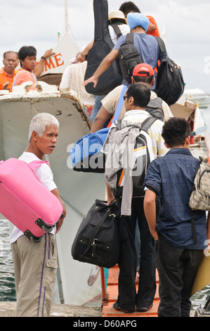 Le persone, i passeggeri, i turisti di salire a bordo di una piccola nave traghetto, salendo una stretta passerella con i loro bagagli - Filippine, Asia Foto Stock