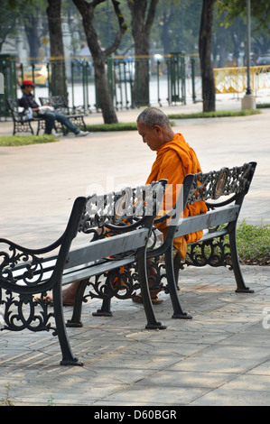 Monaco buddista seduto su una panchina nel parco, Thailandia , il sud-est asiatico Foto Stock