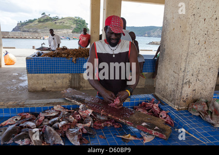 Pescatore locale per l'eviscerazione e la pulizia di teste di pesce al porto mercato in Micoud, St Lucia Foto Stock