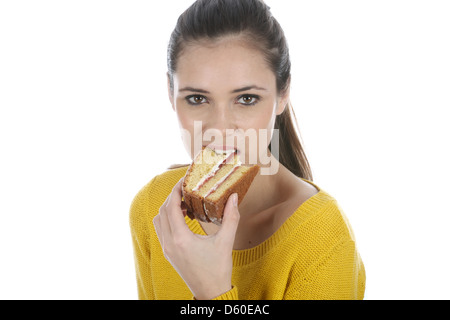 Felice fiducioso giovane donna, Mangiare fetta di fresco Victoria Sponge Cake, isolata contro uno sfondo bianco con tracciato di ritaglio Foto Stock