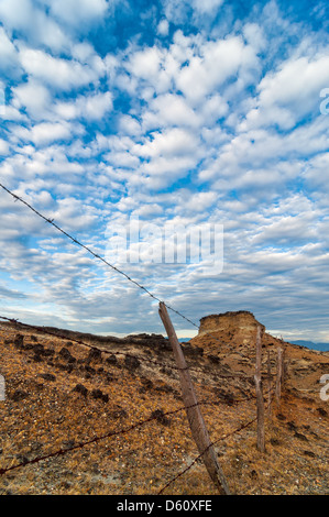 Vecchi e consunti recinzione in un desolato deserto sotto un drammatico cielo blu Foto Stock