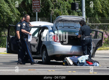 Modesto, California, USA. Il 10 aprile 2013. Modesto poliziotti guardare attraverso una vettura che è stato coinvolto con un drive dal tiro dopo che esso si è schiantato proprio in fondo alla strada della ripresa. Un drive dal tiro vicino all'intersezione della I street e la 5th street in Modesto CA si è conclusa solo per la strada in un incidente di automobile e richiesto il Stanislao County Sheriff Bomb Squad per essere chiamato fuori per un dispositivo sospetto che è situato nel bagagliaio della vettura coinvolta. Bomb Squad membri ID'd il soggetto come una massa simulatore di burst, comunemente utilizzati nella guerra civile reenactments. Credito: ZUMA Press, Inc. / Alamy Foto Stock