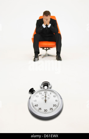 Preoccupato per il businessman seduta con cronometro che rappresenta la perdita di tempo Foto Stock