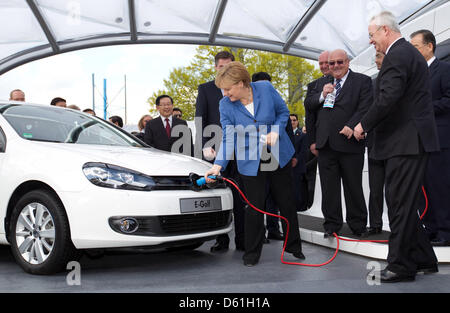 Il cancelliere tedesco Angela Merkel addebita una E-Golf presso lo stabilimento della Volkswagen a Wolfsburg, in Germania, il 23 aprile 2012. Volkswagen presidente del consiglio di amministrazione Martin Winterkorn (R) guarda a. Foto: FRISO GENTSCH Foto Stock