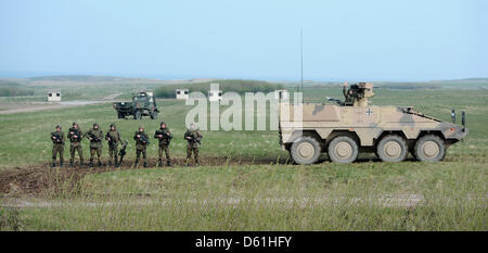 I soldati sono accanto a un combattimento blindati veicolo del GTK tipo Boxer durante una presentazione di sistemi di armi dalla German Federal Defence Force presso la zona di addestramento militare in Putlos, Germania, 25 aprile 2012. I rappresentanti degli Stati membri dell'Organizzazione per la sicurezza e la cooperazione in Europa delle Nazioni unite (OSCE) hanno visitato la presentazione come parte della serie di eventi "ilita Foto Stock