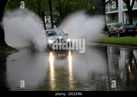 Un auto va lungo una strada allagata dopo tempeste in Duesseldorf, Germania, 20 maggio 2012. Le piogge torrenziali e grandinate causato allagato strade e cantine. Foto: Horst Ossinger Foto Stock