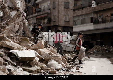 Aleppo, Siria. Tre i bambini raccolgono la legna da ardere da edifici in rovina. Foto Stock