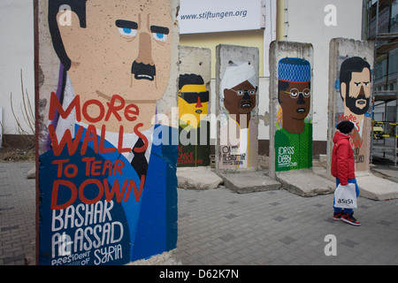 Dittatori nel mondo (incluso il presidente siriano Bashir al-Assad) adornano vecchie sezioni del vecchio Muro di Berlino di fronte alla ex Checkpoint Charlie, l'ex confine comunista tra Berlino Ovest e Berlino Est durante la Guerra Fredda. Il muro di Berlino è stata una barriera costruita dalla Repubblica democratica tedesca, la Germania Est) a partire dal 13 agosto 1961, che completamente tagliata (via terra) a Berlino Ovest dal circostante della Germania orientale e di Berlino Est. .. (Di più nella descrizione). Foto Stock