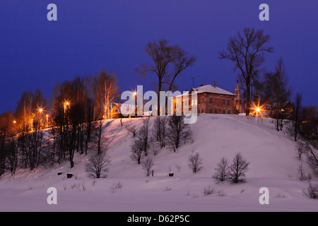 Inverno crepuscolo in una piccola città permanente sulla brusca banca di fiume Foto Stock