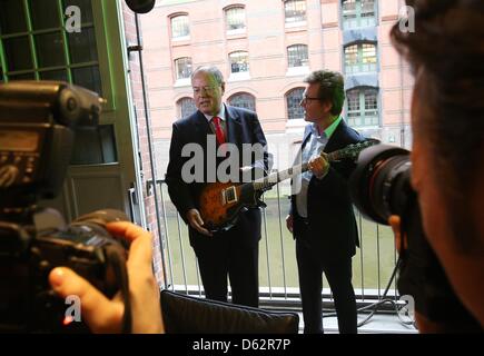 Amburgo, Germania, 11 aprile 2013. Il cancelliere candidato per il Partito socialdemocratico (SPD), Peer Steinbrueck e Bernd Dopp (R), Presidente e CEO di Warner Music Europa Centrale e Orientale, posano con un'e-chitarra dal punk rock band 'Giornata verde' presso la sede di Warner Music Group Germany Holding GmbH di Amburgo, Germania, 11 aprile 2013. Steinbrueck è su una visita di due giorni ad Amburgo. Foto: Christian Charisius/Alamy Live News Foto Stock