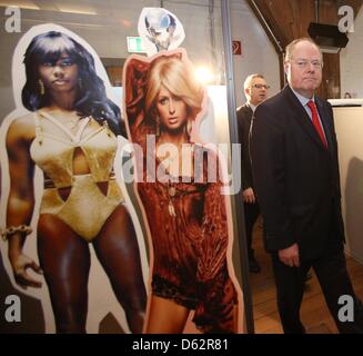 Amburgo, Germania, 11 aprile 2013. Il cancelliere candidato per il Partito socialdemocratico (SPD), Peer Steinbrueck, passeggiate passato figure di cartone di Santigold (L) e Paris Hilton presso la sede di Warner Music Group Germany Holding GmbH di Amburgo, Germania, 11 aprile 2013. Steinbrueck è su una visita di due giorni ad Amburgo. Foto: Christian Charisius/Alamy Live News Foto Stock