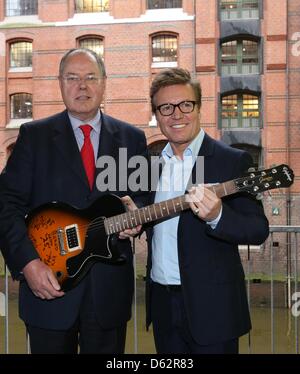 Amburgo, Germania, 11 aprile 2013. Il cancelliere candidato per il Partito socialdemocratico (SPD), Peer Steinbrueck e Bernd Dopp (R), Presidente e CEO di Warner Music Europa Centrale e Orientale, posano con un'e-chitarra dal punk rock band 'Giornata verde' presso la sede di Warner Music Group Germany Holding GmbH di Amburgo, Germania, 11 aprile 2013. Steinbrueck è su una visita di due giorni ad Amburgo. Foto: Christian Charisius/Alamy Live News Foto Stock