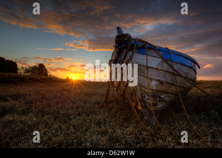 Tramonto su barene dietro la vecchia barca di legno a Burnham Deepdale in Norfolk, Regno Unito Foto Stock
