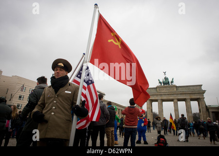 Gli attori in noi e dell'esercito sovietico uniformi tenere bandiere per raccontare la storia tedesca durante la seconda guerra mondiale e dopo la guerra fredda - sotto la Porta di Brandeburgo in Unter den Linden nel centro di Berlino, Germania. Il sito si trova vicino al confine ex comunista tra Berlino Ovest e Berlino Est durante la Guerra Fredda. Anche qui, Berlino è stata separata dalla occupano settori di noi inglesi, francesi e forze sovietiche dopo WW2. (Di più nella descrizione) .. Foto Stock