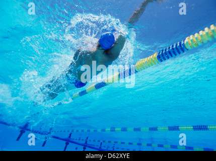 Giovane maschio professionale thlete facendo dorso in piscina Foto Stock