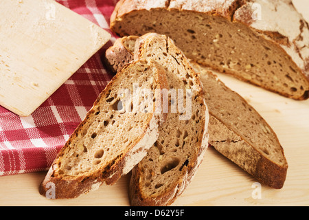 Rustico a fette di pane con un asciugamano da in alto su sfondo di legno con un tagliere Foto Stock