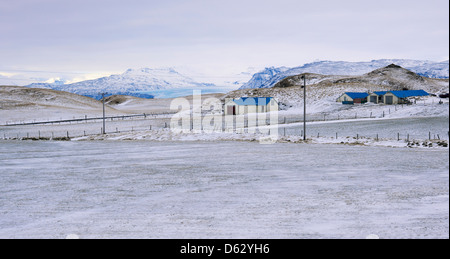 Azienda agricola nel sud-est dell'Islanda in inverno con coperte di neve e di montagna il ghiacciaio Jökulsarlon laguna in bac Foto Stock