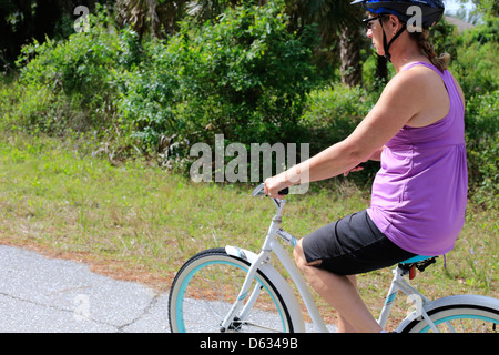 Una di mezza età o senior donna in sella ad una bicicletta su una strada suburbana NEGLI STATI UNITI Foto Stock