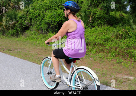Una di mezza età o senior donna in sella ad una bicicletta su una strada suburbana NEGLI STATI UNITI Foto Stock