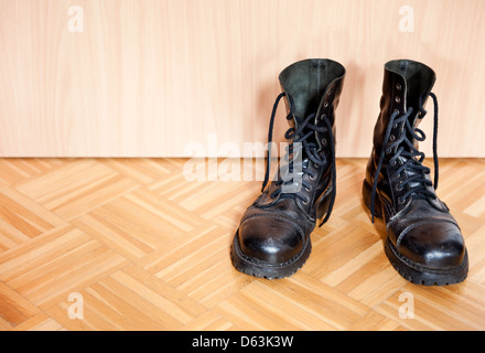 Vecchio usato il nero bovver stivali sul pavimento in parquet Foto Stock