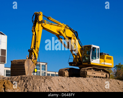 Escavatore giallo terra di scavo sul sito in costruzione Foto Stock
