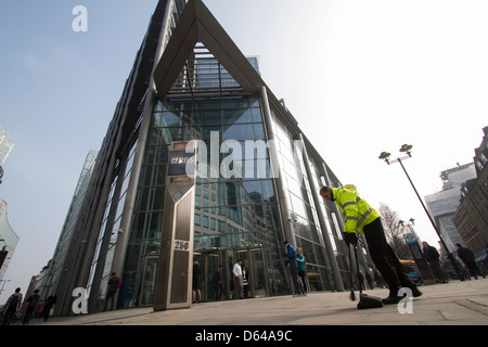 Un pulitore stradale spazza il marciapiede fuori dalla sede centrale della Royal Bank of Scotland (RBS) a Londra, mantenendo la pulizia nell'affollato quartiere finanziario della città, Londra, Regno Unito Foto Stock