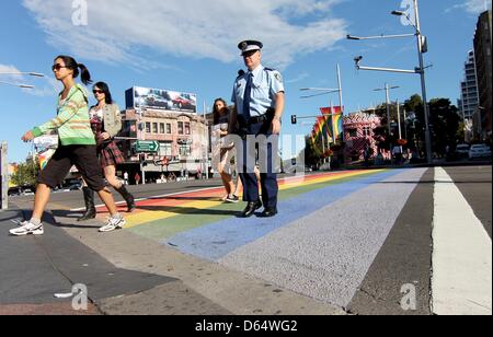 Pedoni e di un funzionario di polizia attraversare una strada attraverso un arcobaleno crosswalk colorato a Sydney, Germania, 07 aprile 2013. Diversi attivisti dipinto colorfull crosswalks tutti su Sidney per protestare contro la reoval di crosswalks colorati. Foto: Sid Astbury Foto Stock