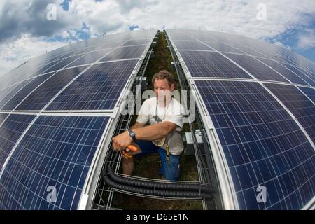 Un elettricista e fissa i cavi per energia solare delle tabelle di grandi impianti fotovoltaici accanto alla autostrada Autobahn A4 vicino Kraftsdorf, Germania, 18 giugno 2012. Con un volume di investimento di 5,3 milioni di euro è previsto per generare 5,7 megawatt. Foto: MICHAEL REICHEL Foto Stock