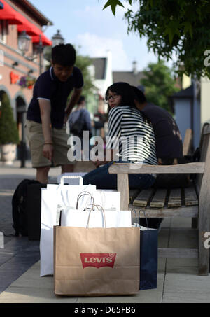 Visitatori riposo da un giro di shopping a un designer outlet store a Roermond, Paesi Bassi, 30 maggio 2012. Il creato artificialmente piccola città per lo shopping è a pochi metri di distanza dal centro della città di Roermond e ha più di 150 negozi outlet sul display. Foto: Daniel Naupold Foto Stock