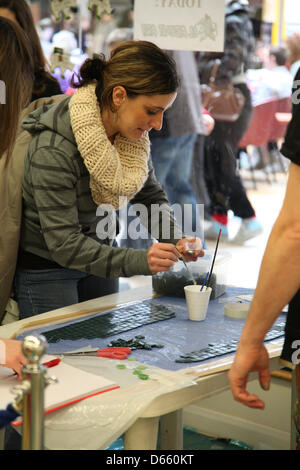 Southampton, Regno Unito. 12 Aprile 2013 - membri del pubblico in posizione sporgente verso il basso di piastrelle a mosaico pronti per essere trasferiti ad una scultura di rhino per Go! I rinoceronti a Marlands Shopping Centre. Il finito di rinoceronti verrà visualizzato sulla scultura in tutta la città di questa estate da luglio a settembre prima di trasferirsi a Marwell Zoo in ottobre dove saranno vendute all'asta. Proventi saranno devoluti Marwell Wildlife, Wessex Heartbeat di alta 5 appello e la Rosa Associazione Strada del. Credito: Rob Arnold/Alamy Live News Foto Stock