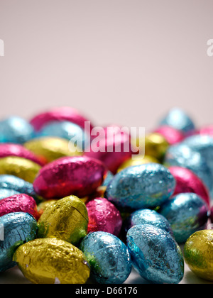 Una foto di una pila di vivaci wraped uova di pasqua di cioccolato su uno sfondo semplice. Foto Stock