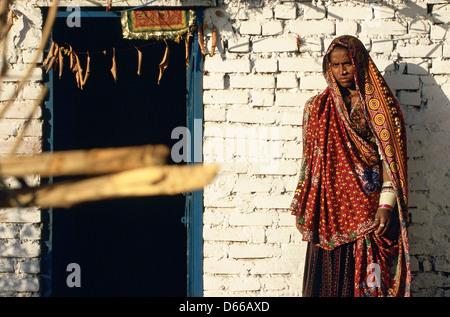 Donna indiana vestito tradizionalmente di fronte alla sua casa. Ella appartiene alla casta Rebari ( India) Foto Stock